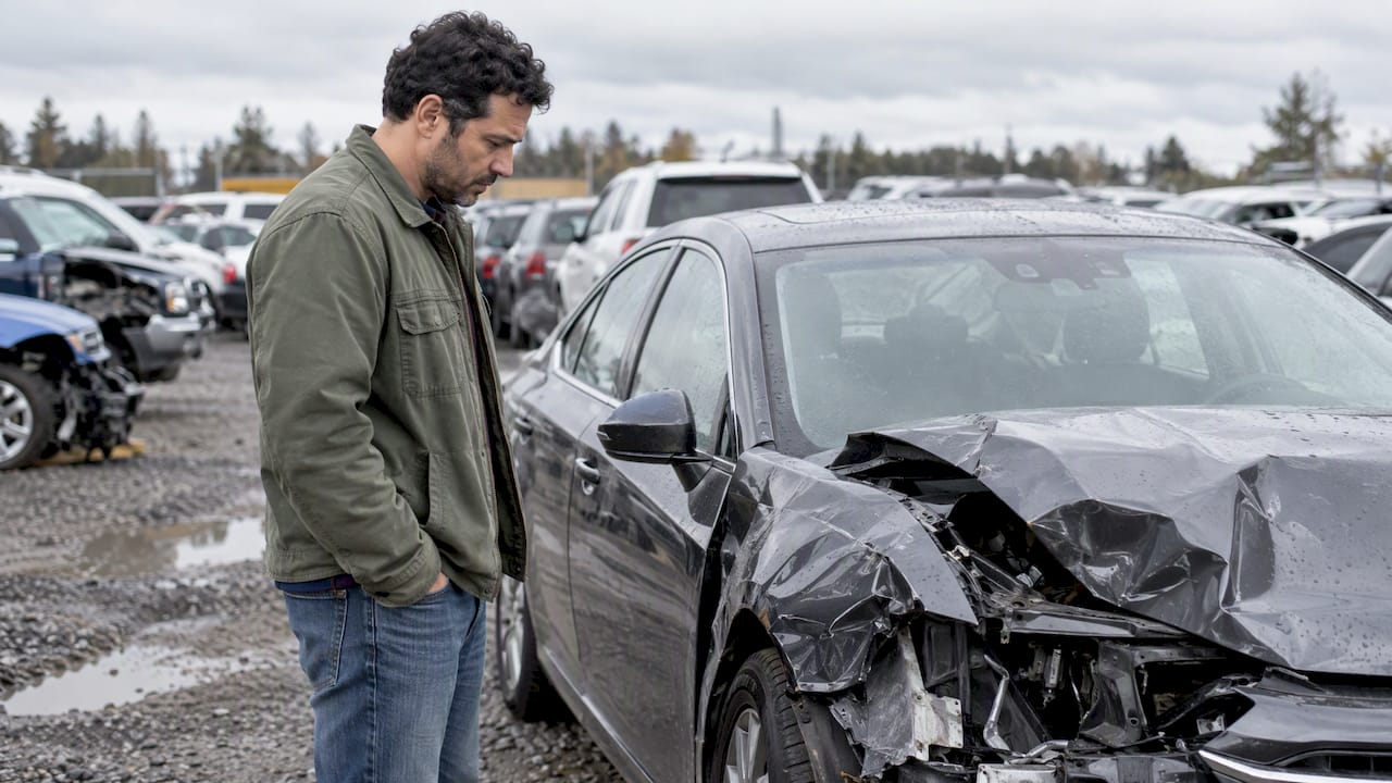 Driver viewing a totaled car in a holding yard